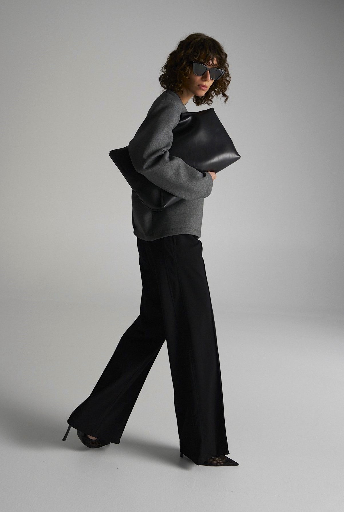 Woman wearing the Mela Purdie Flight Pants in black, styled for travel and work